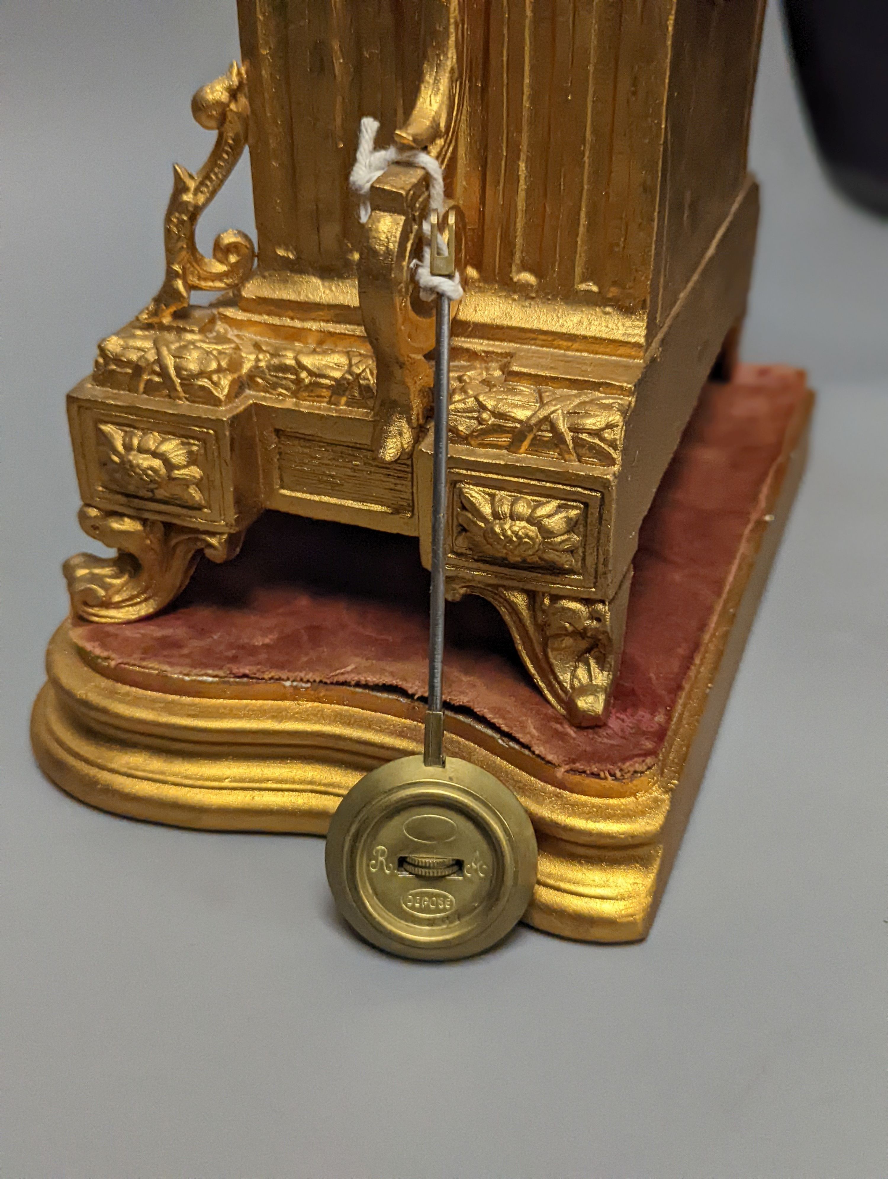 A 19th century gilt metal mantel clock on plinth with key and pendulum 30cm